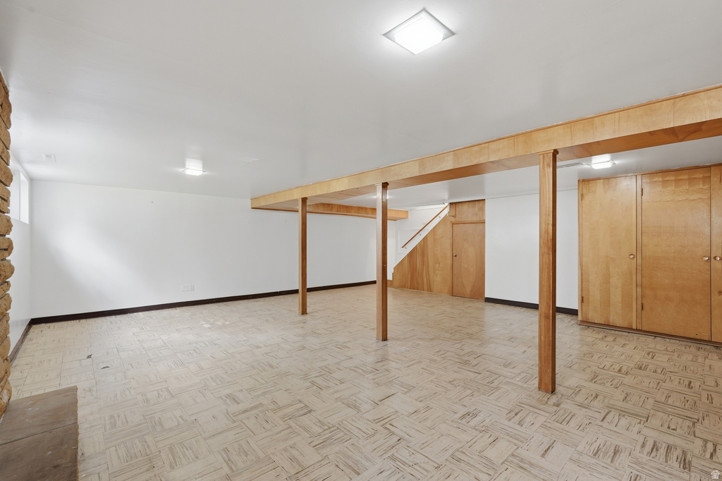 Expansive finished basement featuring wood-finish flooring, a stone-clad fireplace, and built-in wood cabinetry