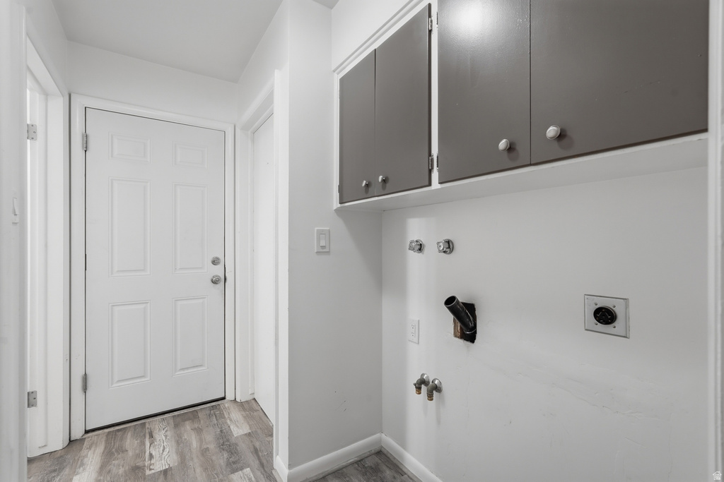 Dedicated laundry area featuring overhead cabinetry, utility hookups, and wood-finish flooring