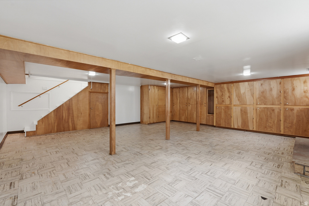 Expansive finished basement featuring wood-paneled walls and a light-toned patterned floor