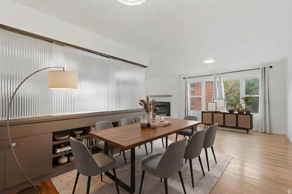 Bright interior space featuring light wood-finish flooring, a white brick fireplace, and built-in shelving with ribbed glass paneling