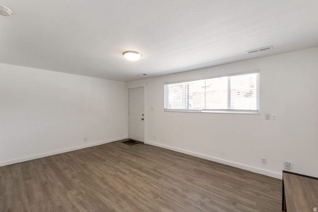 Spacious room featuring wood-finish flooring, white baseboards, and a neutral wall palette