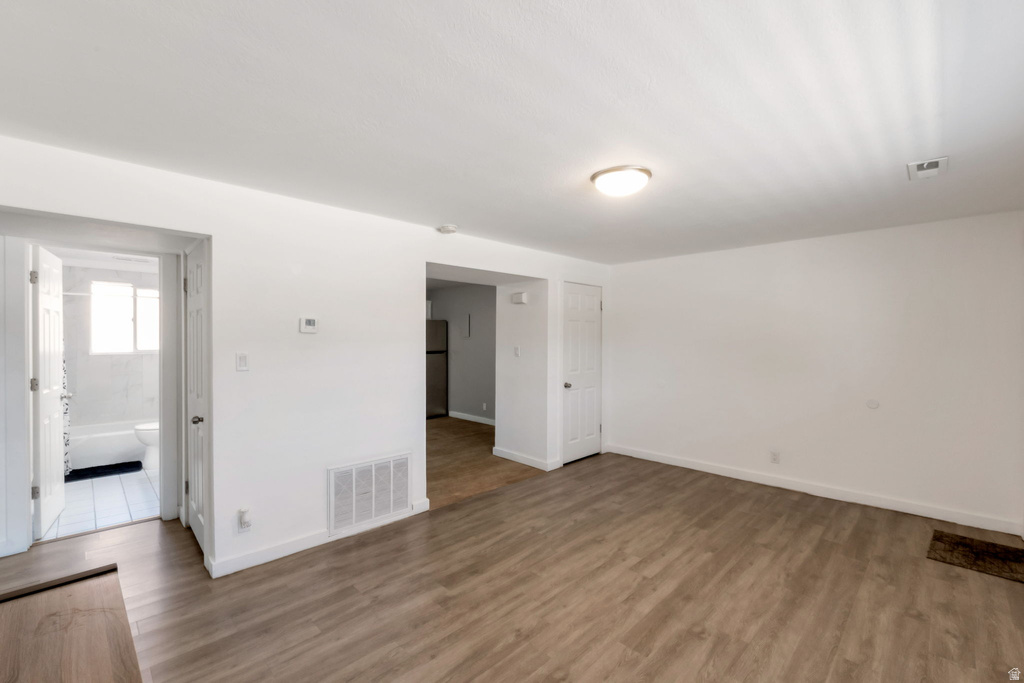 Spacious room with wood-finish flooring, white walls, and a ceiling-mounted light fixture