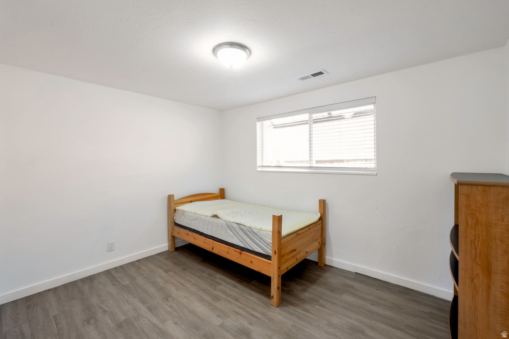 Bright room featuring wood-finish flooring, white walls, and a single window with blinds