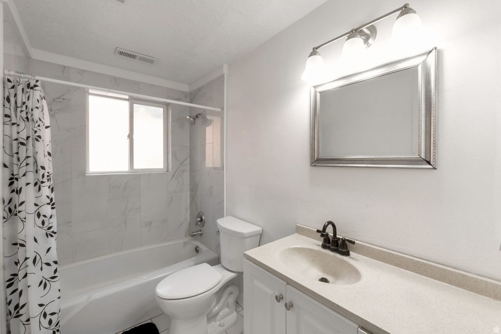 Bathroom featuring a tub/shower combination with white tile surround, a window, and a vanity with an integrated sink and dark bronze faucet