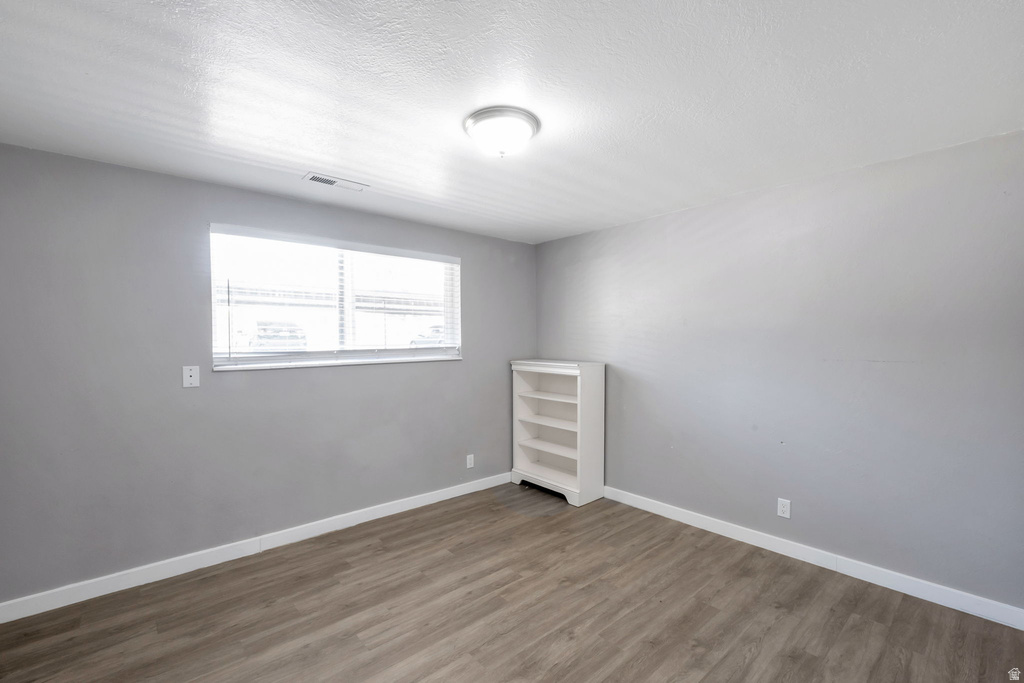 Room with wood-finish flooring, light gray wall paint, and white baseboards