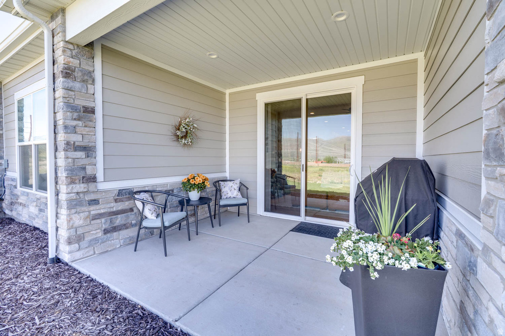 Exterior patio featuring concrete flooring, stone veneer accents, horizontal siding, a large window, and a sliding glass door