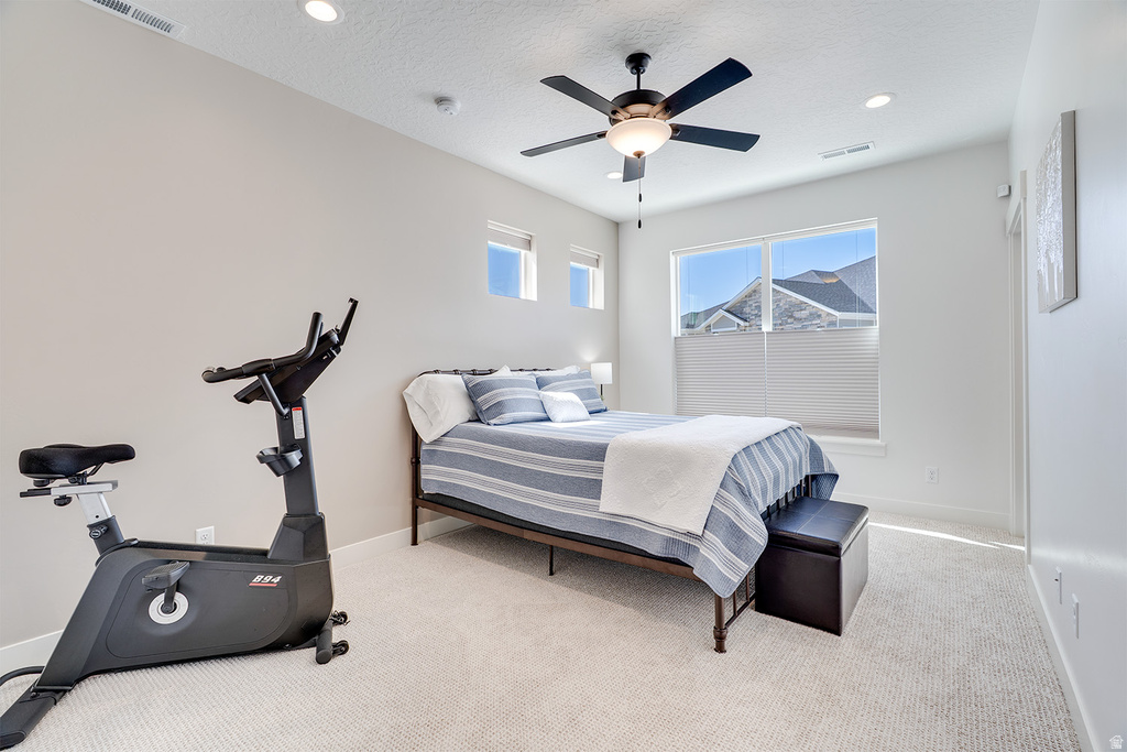 Spacious bedroom featuring light-colored carpet flooring, recessed ceiling lighting, a ceiling fan, and multiple windows with blinds for ample natural light