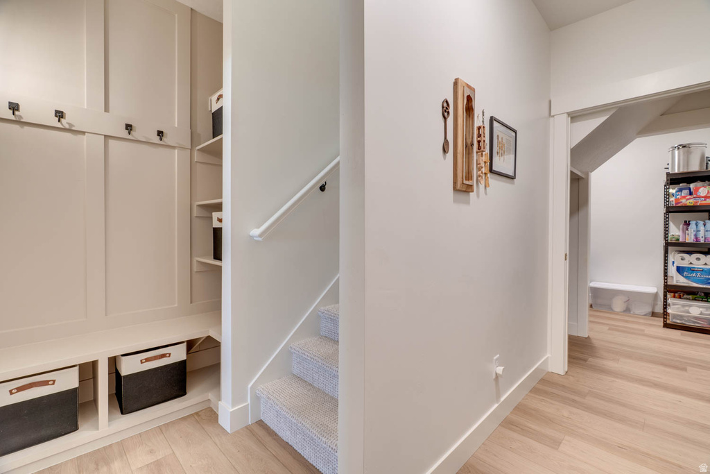 Built-in mudroom bench with coat hooks and integrated shelving, featuring wood-finish flooring