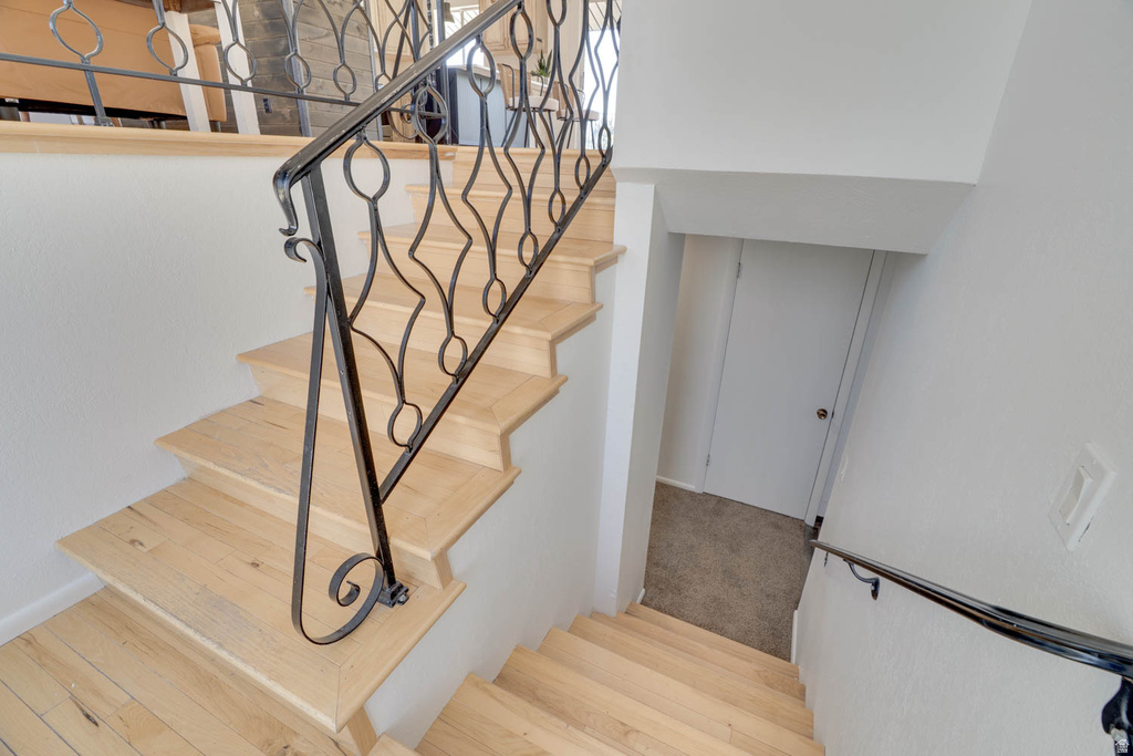 Hardwood staircase featuring ornate wrought iron balusters and a contrasting lower handrail