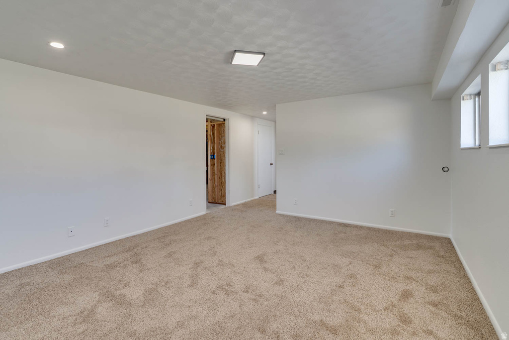 Spacious room featuring neutral carpeting, white painted walls, recessed lighting, and a square flush-mount ceiling light