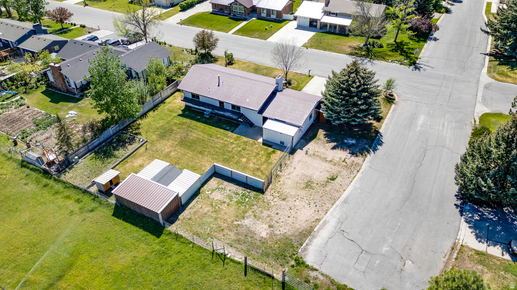 Expansive property featuring a residence with a brown shingle roof, a large grassy yard, and two detached sheds