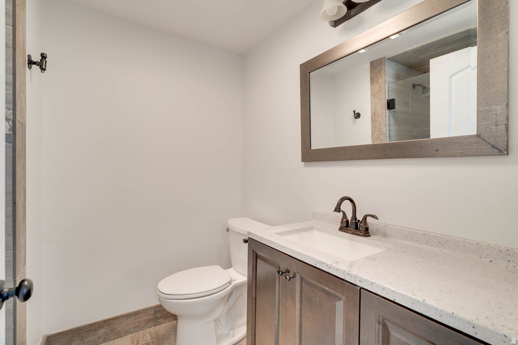Bathroom vanity with a white composite countertop, integrated sink, and bronze-finish faucet