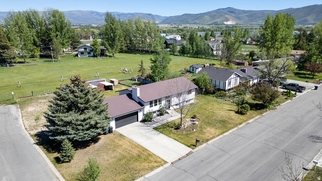 Ranch-style residence featuring a prominent front-facing garage, concrete driveway, and mature landscaping
