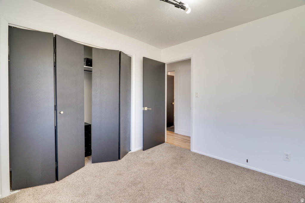 Carpeted room with white walls, featuring bi-fold closet doors and a standard interior door with contemporary hardware