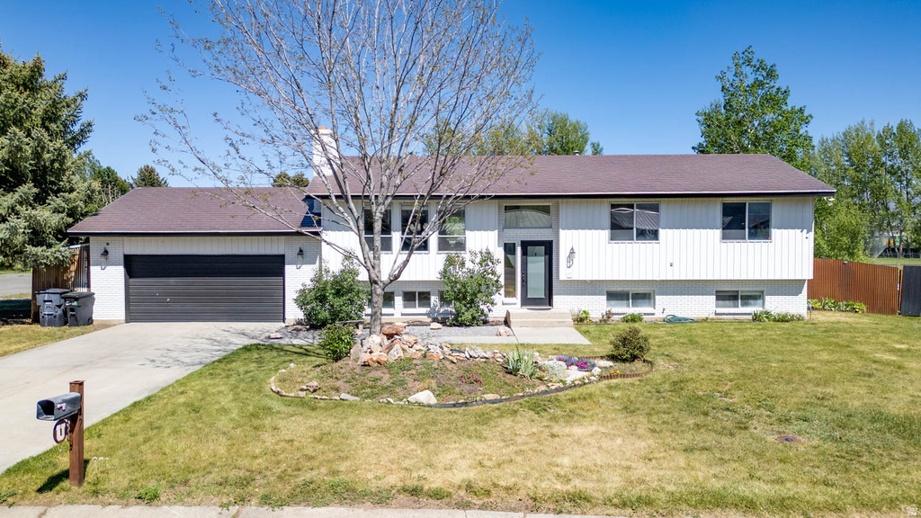 Split-level home featuring white siding, a dark roof, and an attached two-car garage
