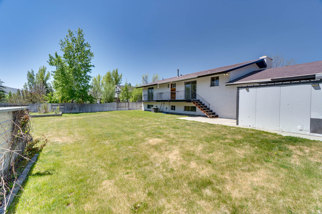 Expansive rear yard featuring green lawn, mature perimeter trees, and a full privacy fence