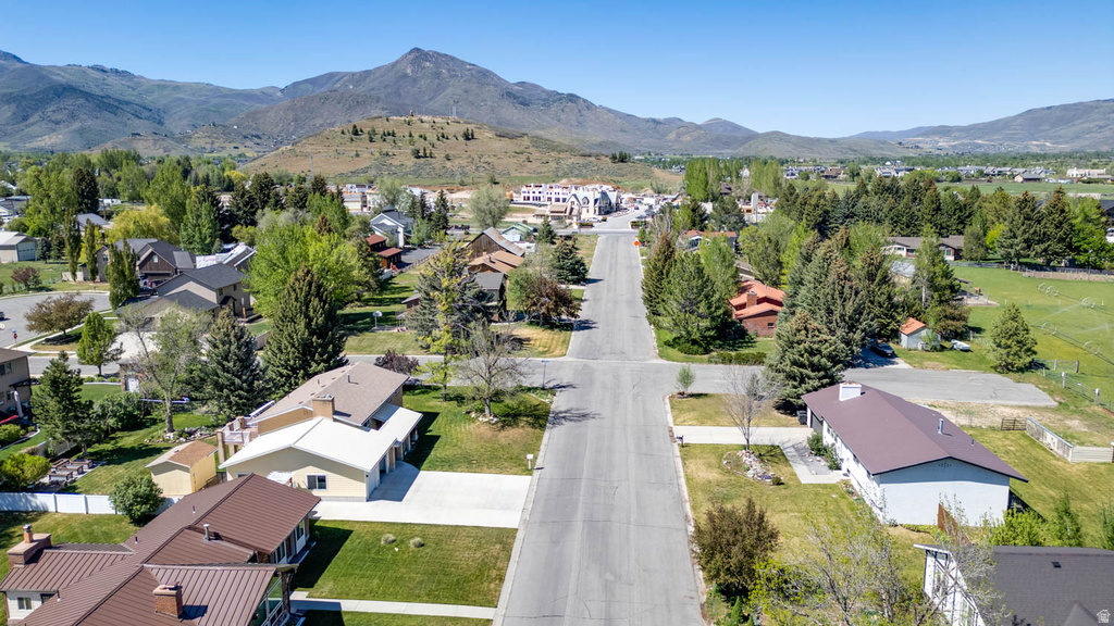 Residential street with established homes, mature trees, and mountainous background scenery
