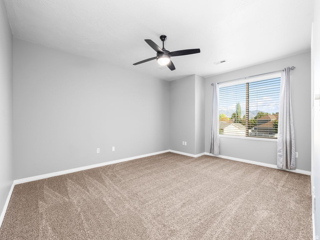 Spacious room featuring neutral carpeting, a large window with blinds, and light-colored walls