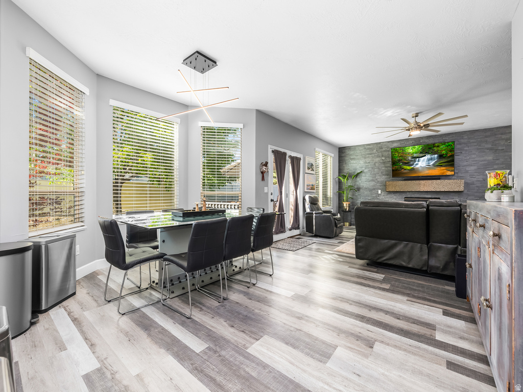 Open-concept living area featuring light gray wood-finish flooring, a modern linear chandelier, and ample natural light from multiple windows