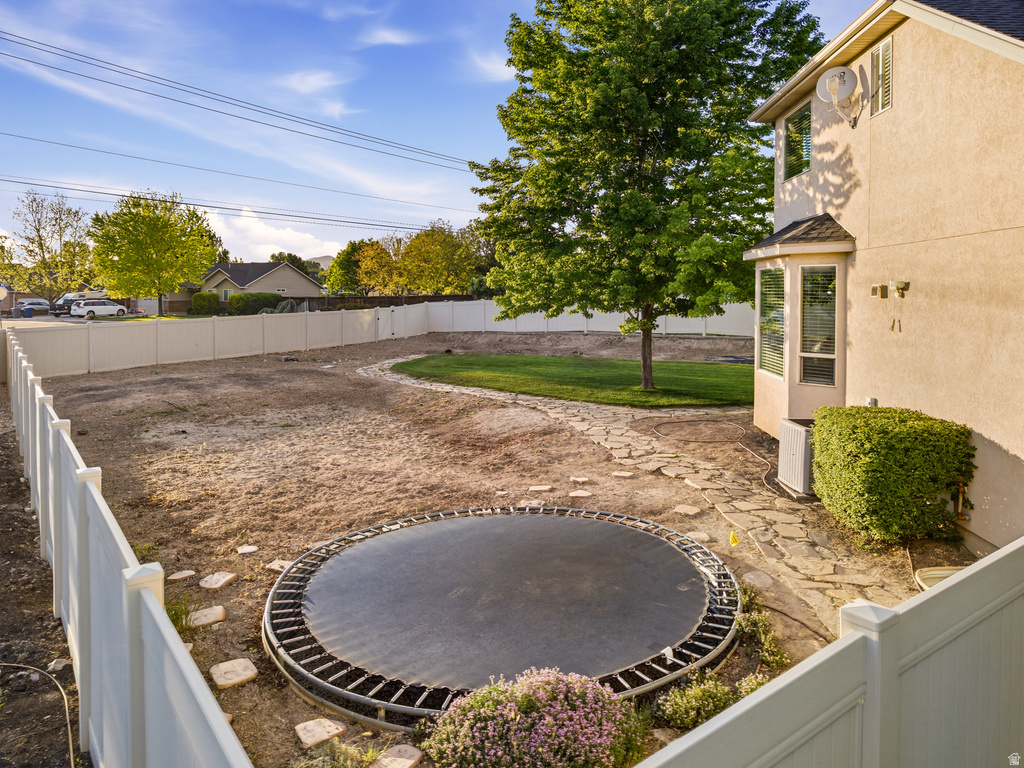 Spacious rear yard featuring a partial flagstone pathway, mature trees, and privacy fencing