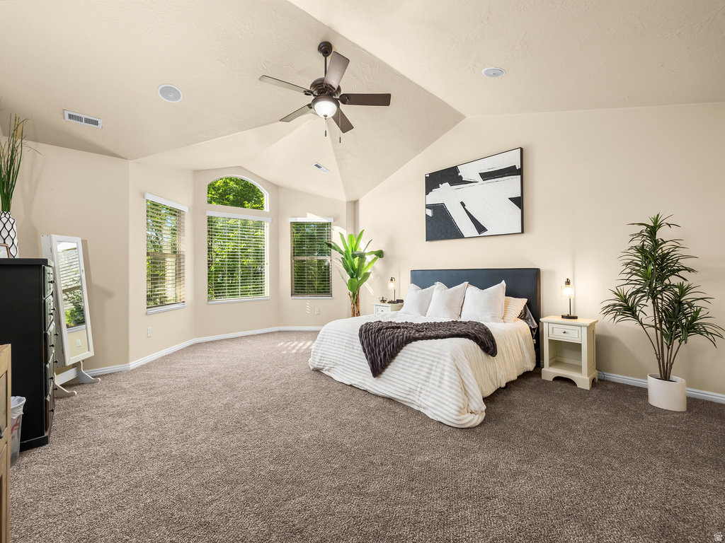 Spacious room featuring vaulted ceilings, recessed lighting, a ceiling fan, bay windows with blinds, and neutral-toned carpeting