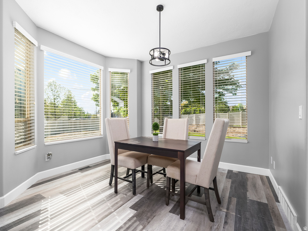 Dining area featuring a bay window with multiple windows, wood-finish flooring, and a contemporary ceiling light fixture