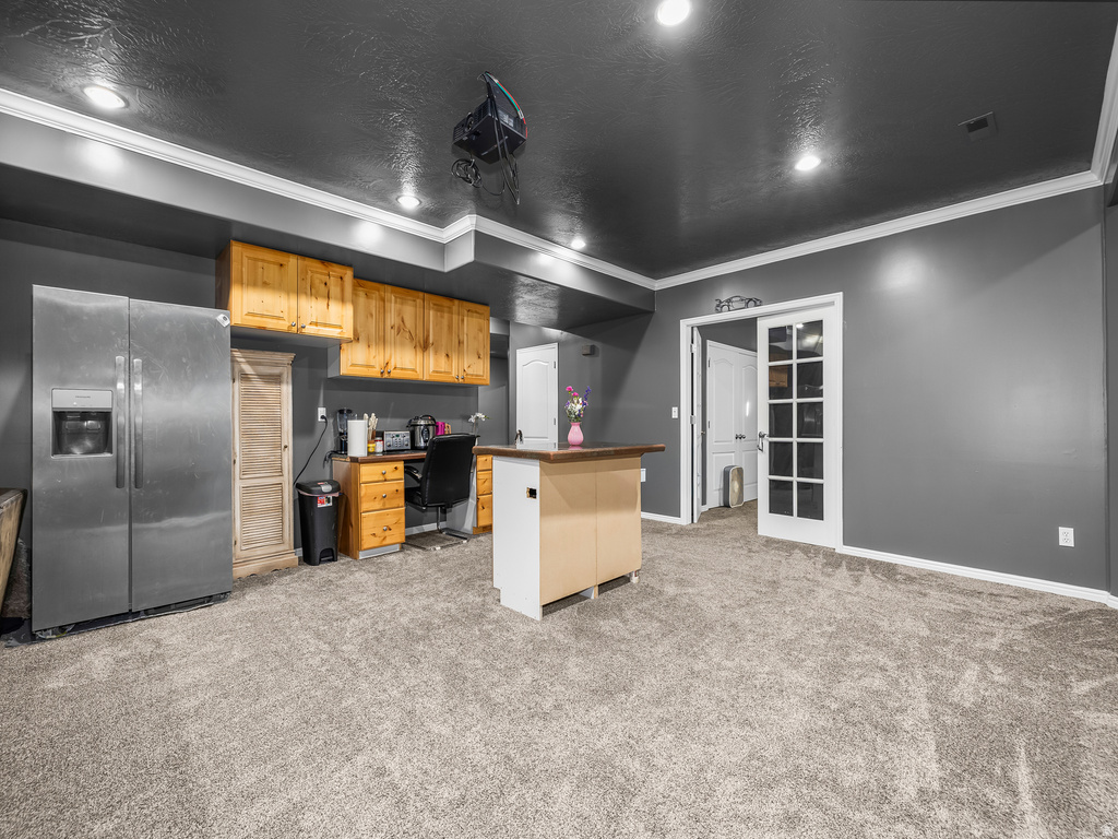 Carpeted room featuring a built-in wood cabinetry workspace, a stainless steel refrigerator, and recessed lighting