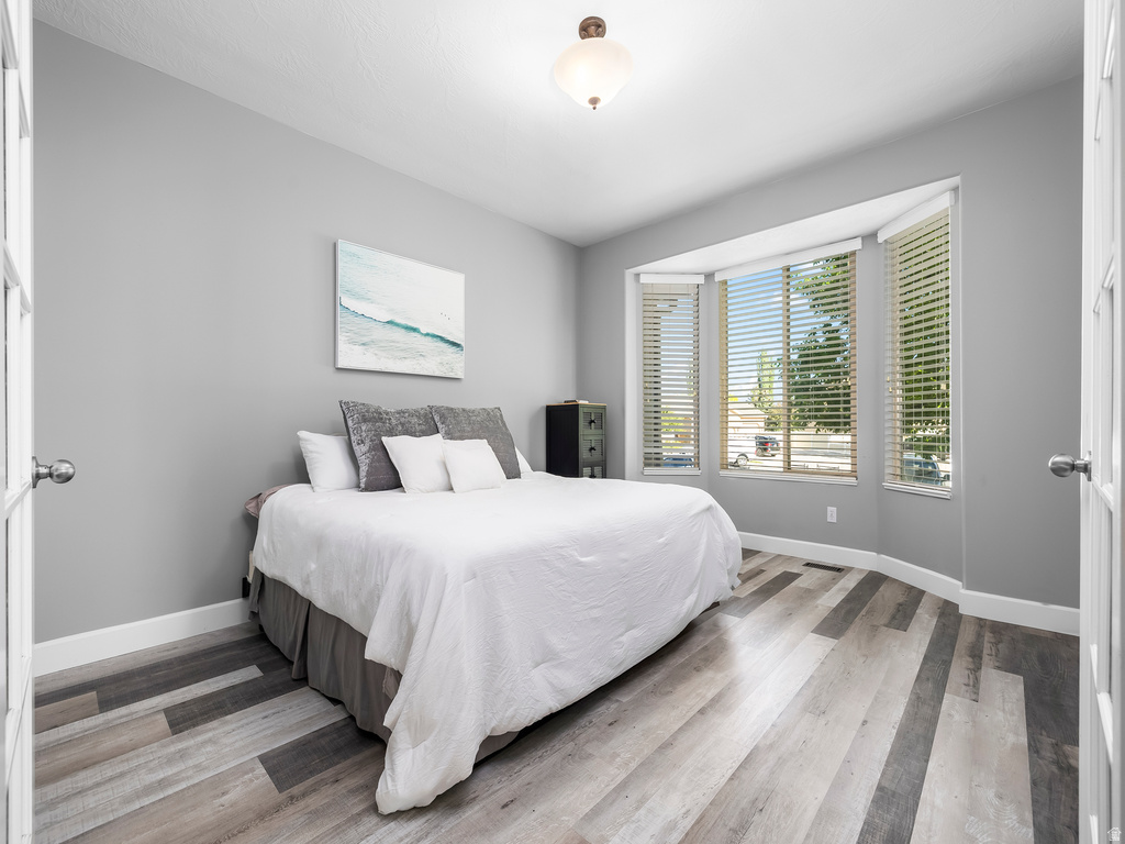 Room featuring a bay window, wood-finish flooring, and white baseboards