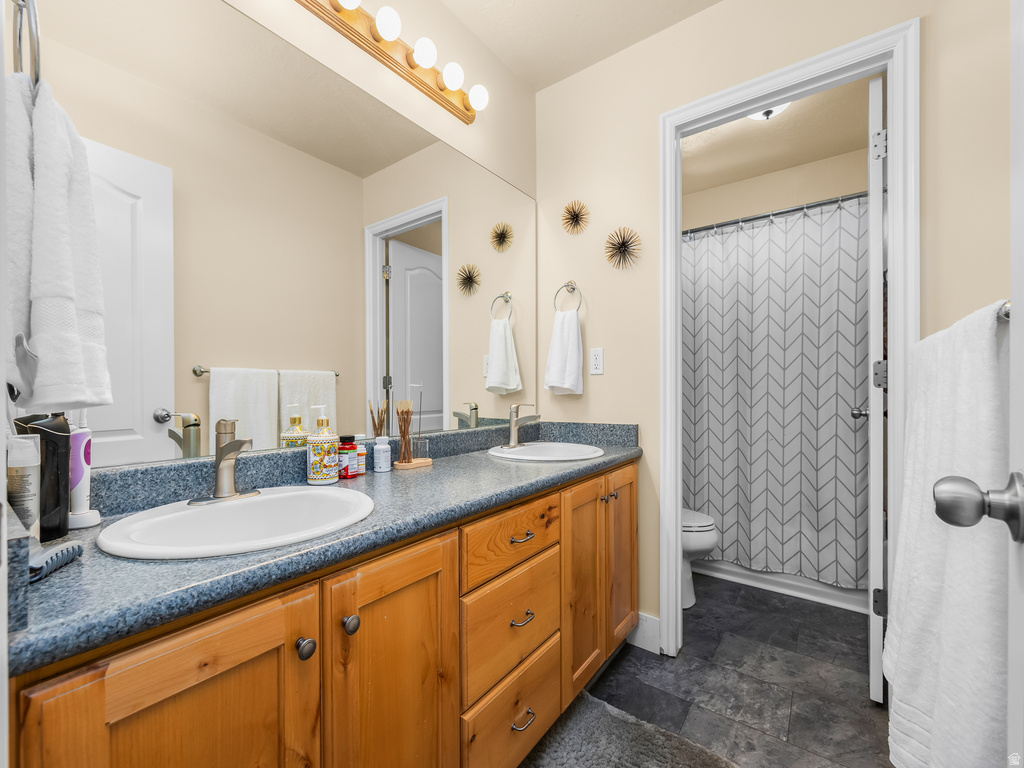 Double vanity with light wood cabinetry, blue speckled countertop, and chrome faucets