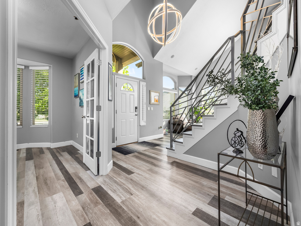 Entryway featuring variegated wood-finish flooring, a contemporary black metal stair railing, and a vaulted ceiling with a modern spherical light fixture