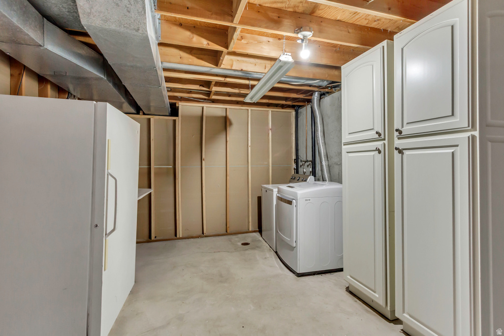 Utility area featuring a washer and dryer, concrete flooring, exposed ceiling joists, and white built-in cabinetry