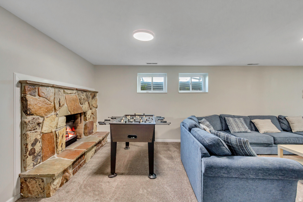 Stone fireplace with an extended hearth, recessed lighting, and soft carpet flooring