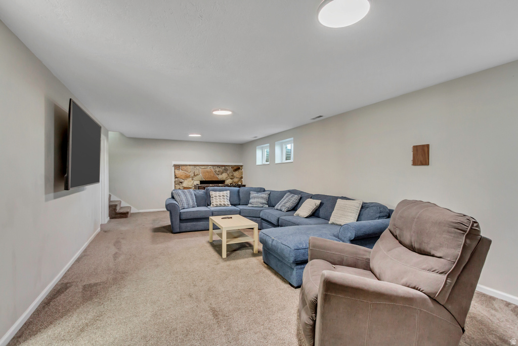 Spacious entertainment area featuring neutral-toned carpeting, recessed ceiling lighting, and a stone-clad fireplace