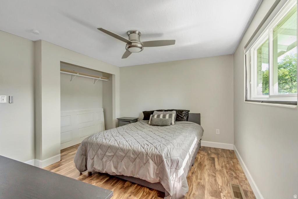 Bedroom featuring wood-finish flooring, a ceiling fan, and a built-in closet with shelving and hanging rod