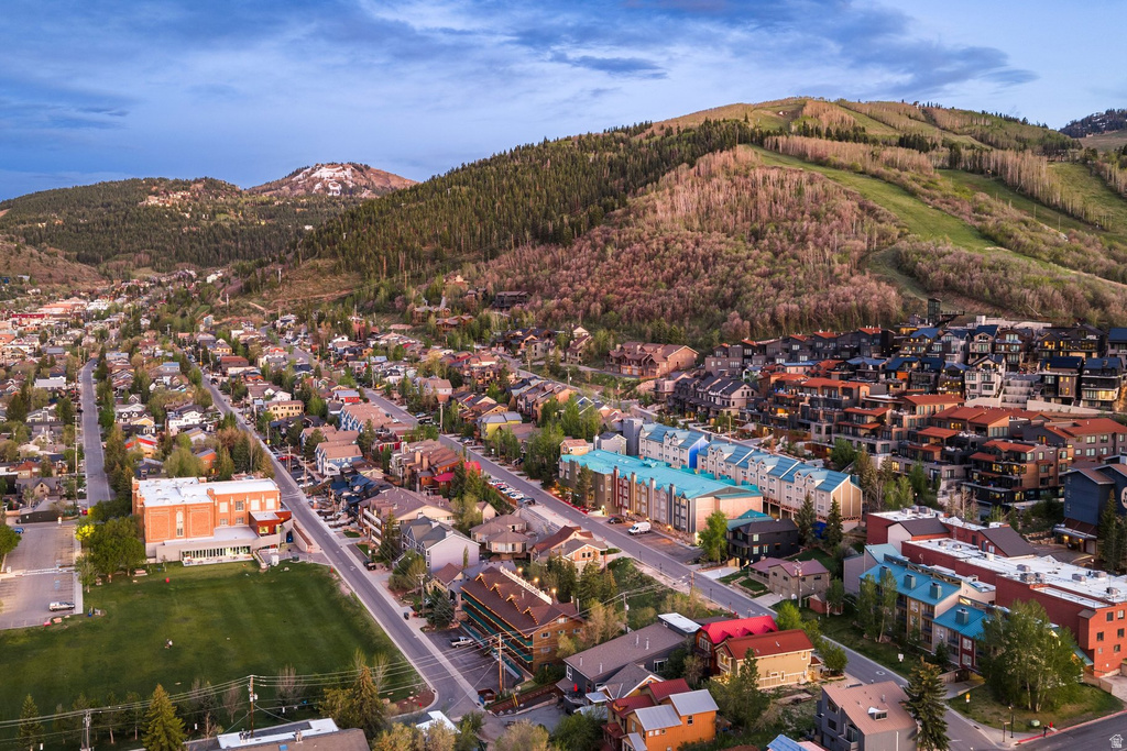 Aerial perspective of a mountain community featuring residential properties, commercial structures, and a prominent green space