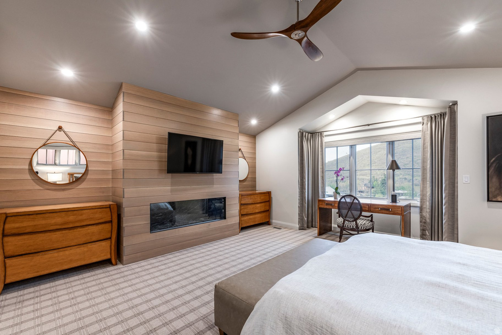 Vaulted ceiling bedroom with a wood-paneled accent wall featuring a built-in linear fireplace