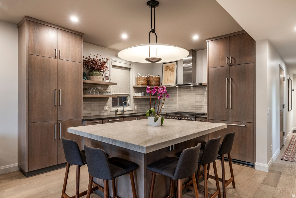 Contemporary kitchen featuring wood-finish cabinetry, a large center island with seating, stainless steel appliances, and wood-finish flooring