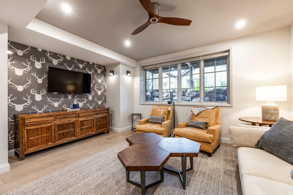 Recreation room featuring recessed lighting, a wood-finish ceiling fan, wood-finish flooring, a decorative accent wall, and multiple window openings