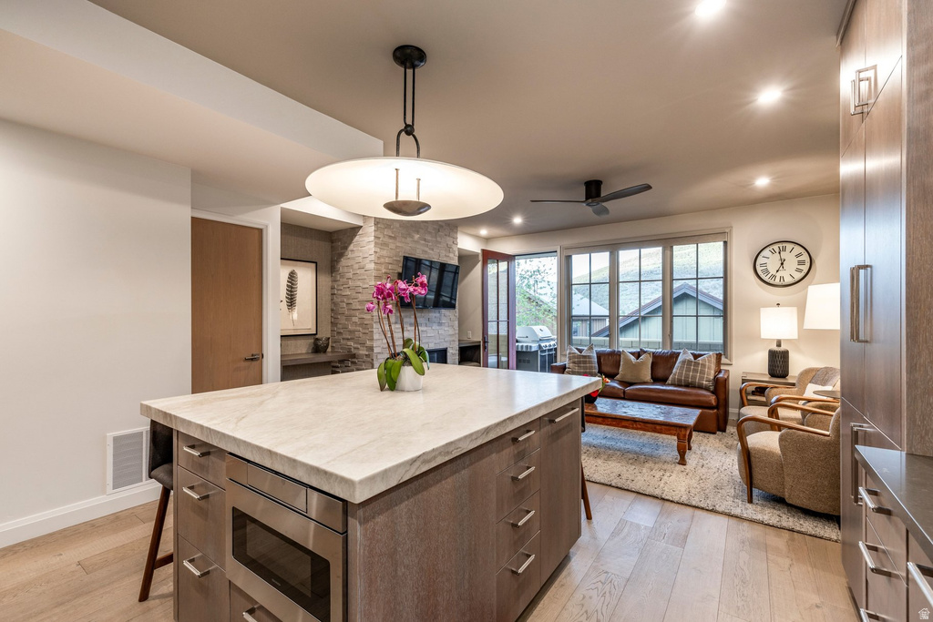 Kitchen island featuring a light-toned countertop, integrated microwave, and dark wood-finish cabinetry