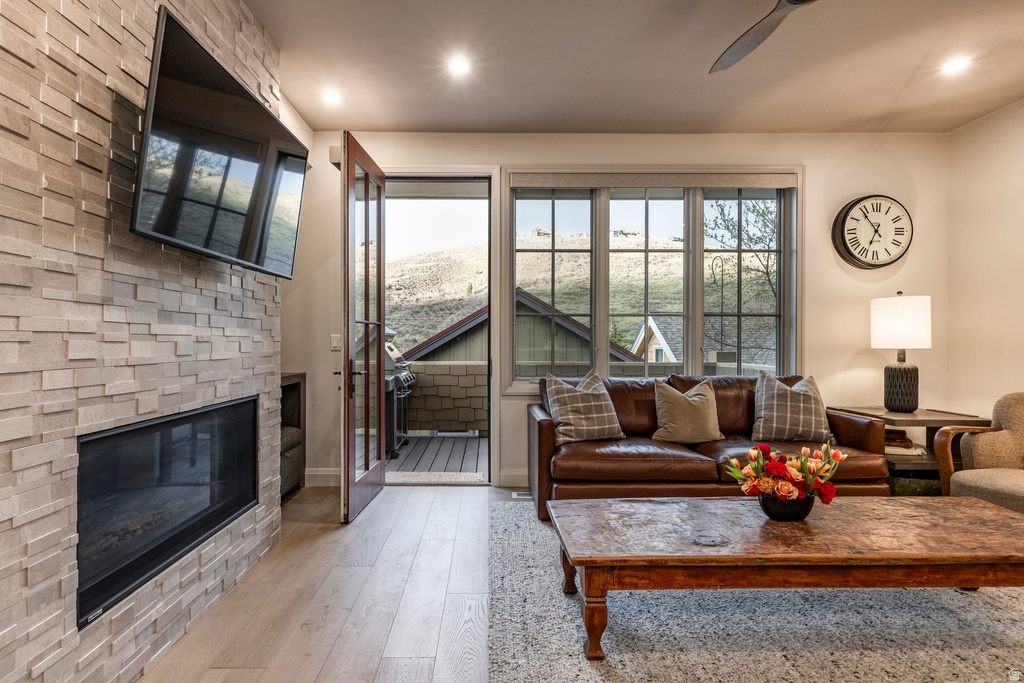 Living area featuring a floor-to-ceiling stacked stone fireplace, wood-finish flooring, recessed lighting, and a multi-pane window with mountain scenery
