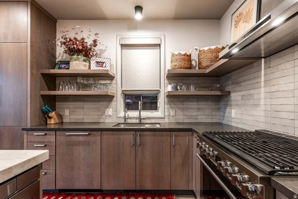 Modern kitchen featuring wood-finish cabinetry, dark countertops, and a white tile backsplash