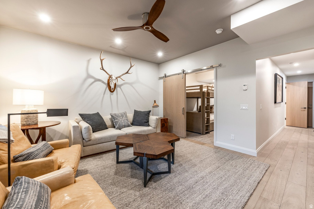 Spacious living area featuring light-toned walls, recessed lighting, and a wood-finish ceiling fan