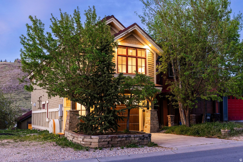 Craftsman-style exterior featuring a prominent gable roofline, wood-finish siding, and a stone-clad foundation