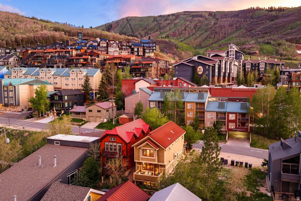 Sloping hillside community featuring multi-story residential structures with varied architectural styles, red and blue metal roofs, and multiple balconies