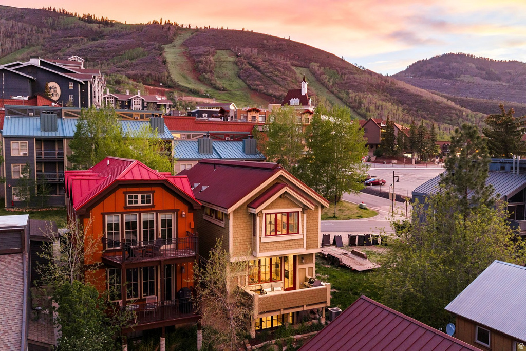 Multi-story residence featuring a vibrant red metal roof, orange siding, and a prominent balcony