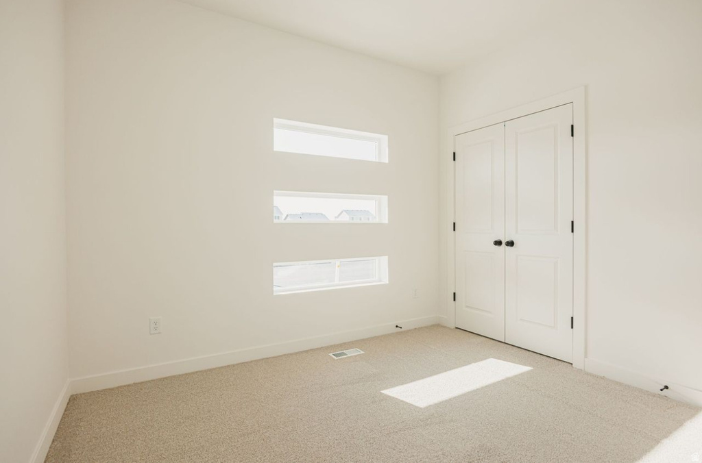 Room with neutral carpeting and white walls