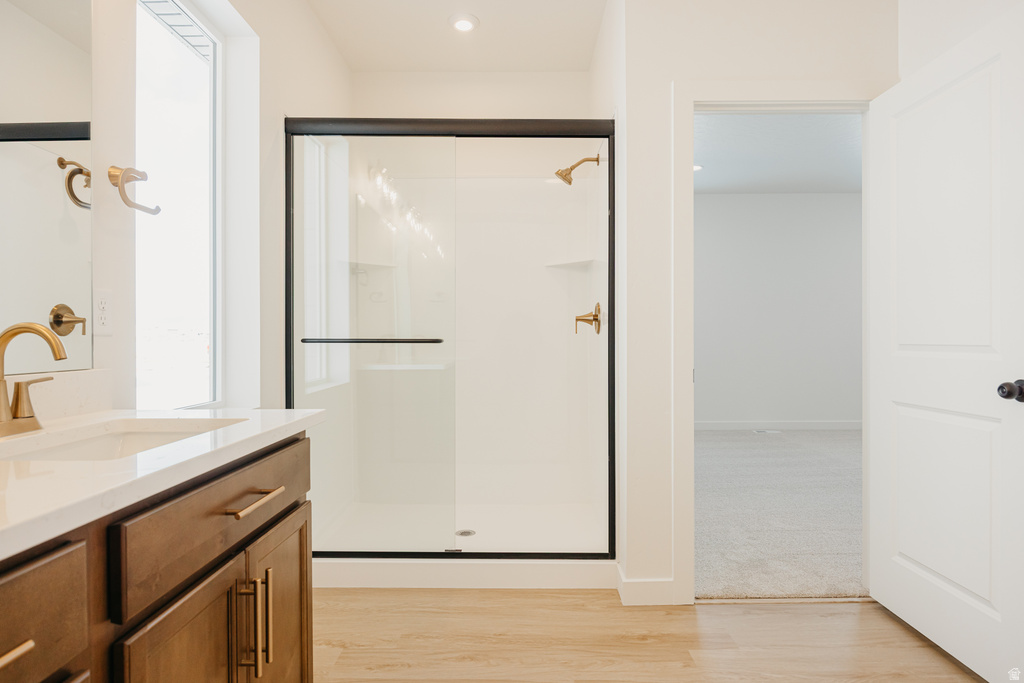 Bathroom featuring a glass-enclosed shower with bronze-finish fixtures, a single vanity with wood-finish cabinetry, a white countertop, and a rectangular undermount sink