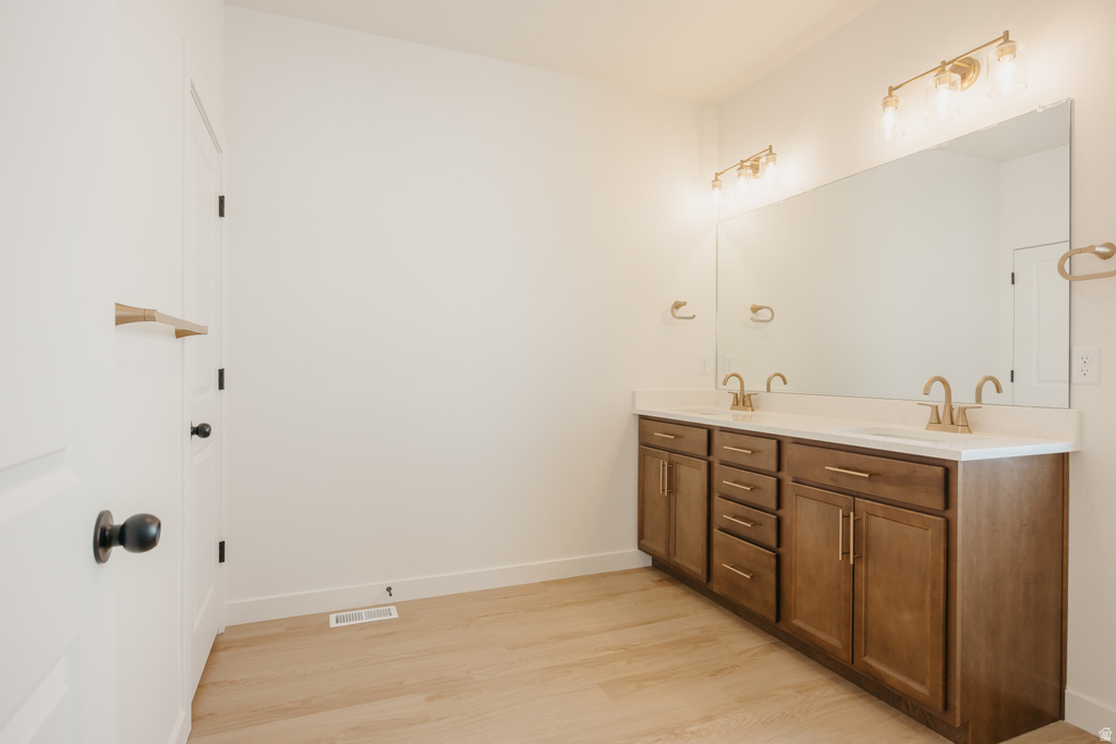 Dual vanity with wood-finish cabinetry, white countertops, and gold-tone fixtures