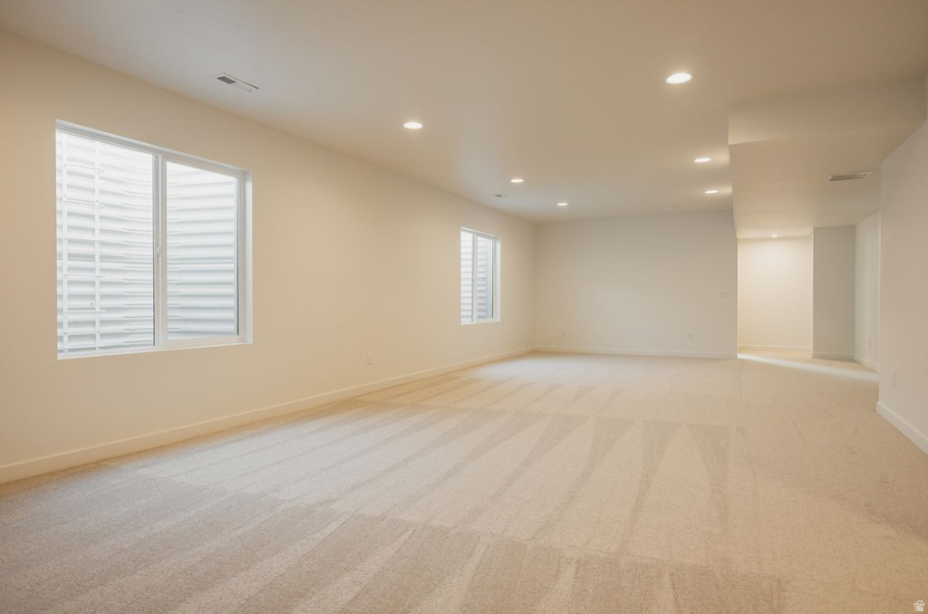 Spacious room featuring light-toned carpet flooring, recessed ceiling lighting, and multiple egress windows