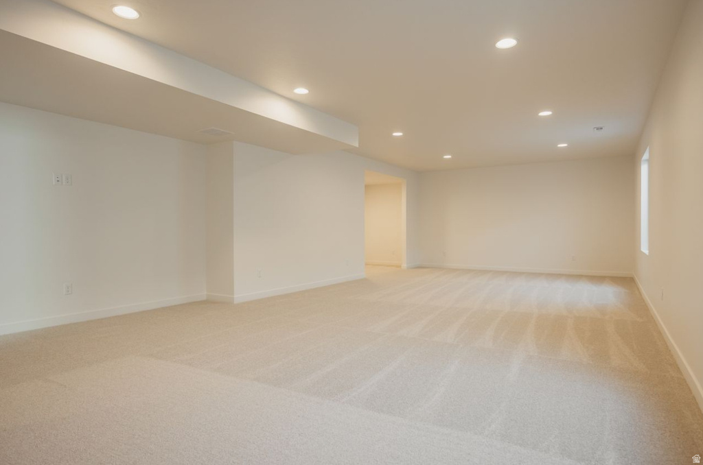 Spacious open-concept room featuring neutral-toned carpet flooring, recessed lighting, and white walls